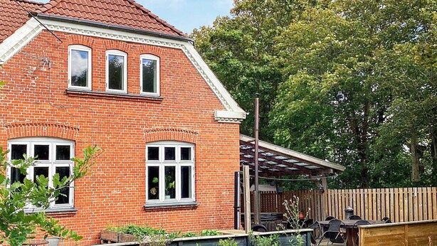 A brick house with a covered patio, a fenced yard, and a small garden area. - 5 Star Holiday Home in Grindsted (Grindsted)