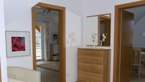 Une pièce comprenant une armoire en bois, un miroir, un tableau encadré et une chaise.