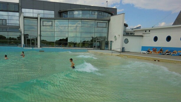An indoor swimming pool with clear water, a modern building with large windows, and a few people swimming. - Friesengold Modern Retreat (Esens)