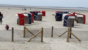 A beach with numbered beach huts and a fenced area. - Friesengold Modern Retreat (Esens)