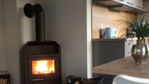 Una cucina moderna con stufa a legna, un tavolo da pranzo e una pianta in vaso.