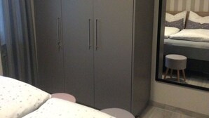 Una camera da letto con un letto, un armadio, uno sgabello e una finestra.