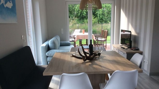 Un'area pranzo moderna con tavolo in legno, sedie bianche e lampadario.