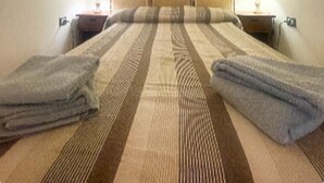 A room with a bed, two bedside tables, a lamp, and a window with curtains. - 1 Bedroom Apartment in Alghero (Alghero)