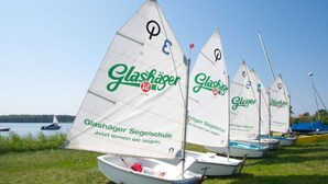 Several sailboats with "Glashäger Segelschule" written on their sails, parked on a grassy area near a body of water. - Chudzik Modern Retreat (Rerik)