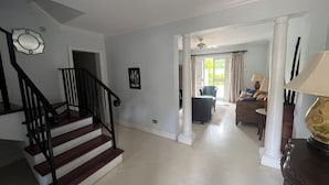 Een ruime woonkamer met een trap, een eethoek en uitzicht op de omgeving.
