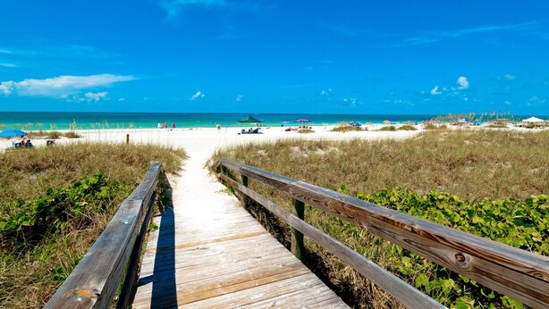 A wooden boardwalk leading to a beach with clear skies and calm waters. - Sunset FantaSea at One Particular Harbour 380-202 · Sound Views · 3BR (Bradenton)