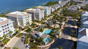 A coastal residential area with modern buildings, a swimming pool, and a view of the ocean. - Sunset FantaSea at One Particular Harbour 380-202 · Sound Views · 3BR (Bradenton)