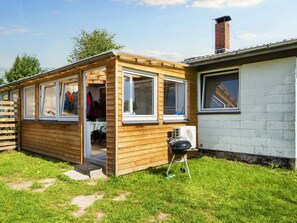 Une maison mobile en bois dotée d’un porche couvert, d’un petit garage attenant et d’une cheminée.