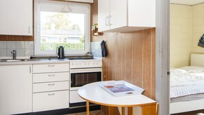 A compact kitchen with a window, a stove, and a small table with a magazine. - 3 Person Holiday Home in Sydals (Sydals)