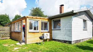A small, single-story wooden house with a white exterior, a chimney, and a small attached garage. - 3 Person Holiday Home in Sydals (Sydals)