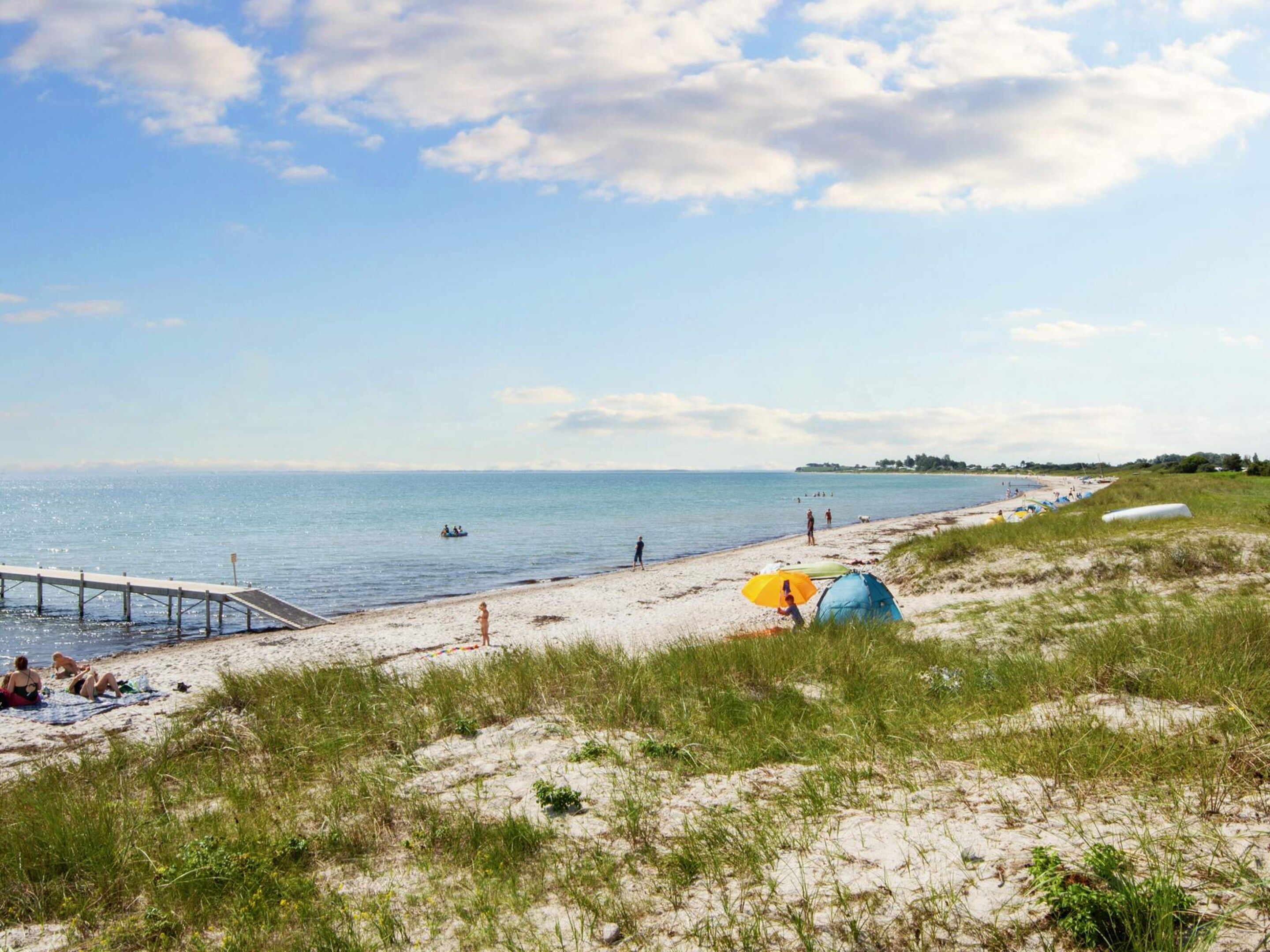 A beach with a pier, tents, and people.