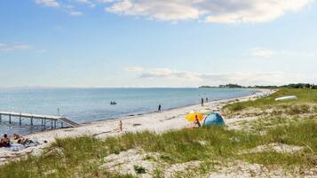 A beach with a pier, tents, and people.