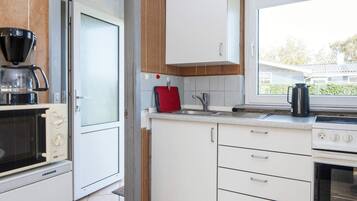 Una cocina compacta con microondas, estufa y lavamanos.
