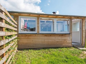 Une cabane en bois avec un jardin clôturé, de grandes fenêtres et une porte.