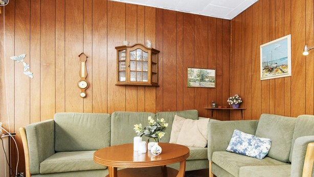 A cozy living room with a green sofa, a wooden table with a vase of flowers, a wooden cabinet, and a painting on the wall. - 3 Person Holiday Home in Sydals (Sydals)