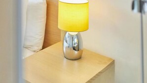 A bedside table with a lamp, a white pillow, and a wooden headboard. - Jackson Court Apartment 3 (Redcar)