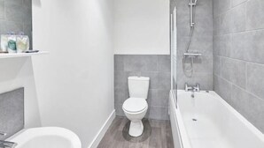 A modern bathroom with a toilet, bathtub, and shower. - Jackson Court Apartment 3 (Redcar)