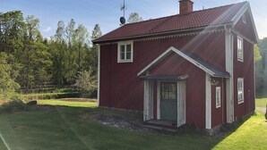 Une maison en bois rouge, avec un toit à pignon et une antenne parabolique.