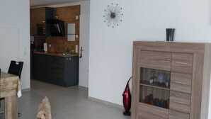 A modern kitchen with dark cabinets, a microwave, and a wooden island. A red vase is on the floor next to a wooden cabinet with glass doors. - Todtmoos Modern Retreat (Todtmoos)