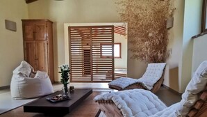 Ein Zimmer mit Holzboden, einer Couch, einem Sitzsack, einem Couchtisch und einem Holzschrank.