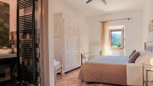 Ein Schlafzimmer mit Bett, Fenster, Heizkörper und Deckenventilator.