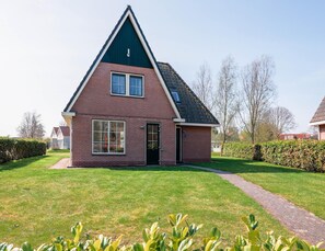 A single-story brick house with a gabled roof, a front door, and a small front yard with a pathway leading to the entrance. - Villa Near the Lake in Makkum (Makkum)