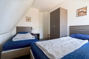 A bedroom with two beds, a wardrobe, and a painting on the wall. - Villa Near the Lake in Makkum (Makkum)