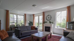 Una sala de estar moderna con chimenea, ventanas amplias y un reloj en la pared.