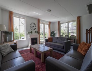 A living room with a fireplace, a sofa, a coffee table, and a television. - Villa Near the Lake in Makkum (Makkum)