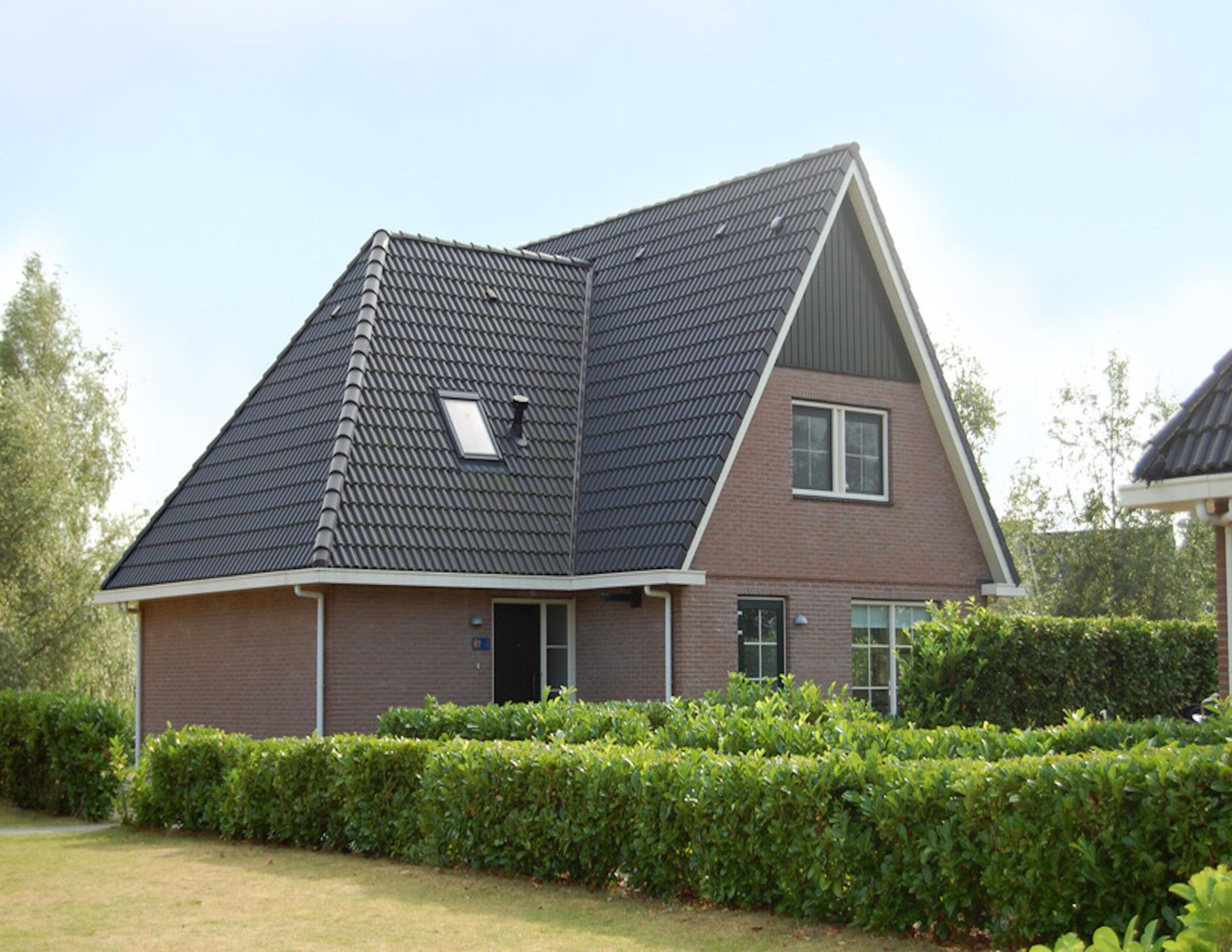 A two-story house with a steeply pitched roof, a visible skylight, and a brick facade.
