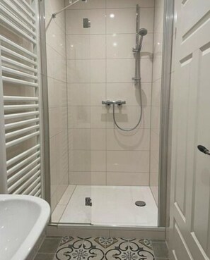 A shower with a glass door, a white sink, and a patterned floor. - Nice Apartment in Klein Upahl (Klein Upahl)