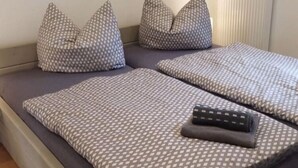 A bed with grey and white patterned bedding, a remote control, and two decorative pillows. - Nice Apartment in Klein Upahl (Klein Upahl)