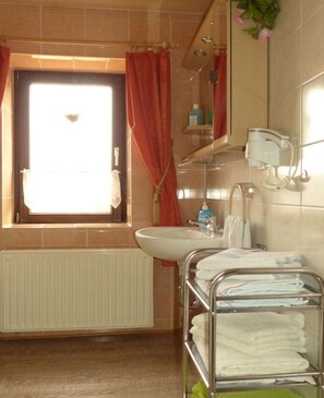 A bathroom with a window, a sink, a towel rack, and a mirror. - Holiday Apartment Family Kreissl (Oberwiesenthal)