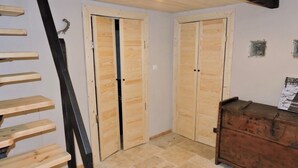 Une pièce avec un escalier en bois, deux portes en bois, une commode en bois et un sol carrelé.