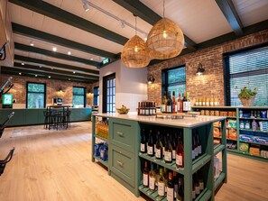 A bar area with wooden floors, green bar stools, and a variety of bottles on shelves. - Safari Tent Near Lauwersmeer Park (Vierhuizen)