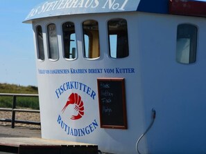 A boat with a sign reading "Fischkutter Butjadingen" and a chalkboard menu.