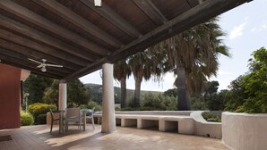An outdoor patio with a wooden pergola, a table with chairs, and a seating area with planters. - Venere Comfortable Holiday Residence (Maracalagonis)