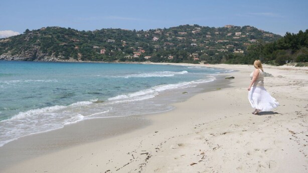 A beach with a person in a white dress walking along the shore. - Venere Comfortable Holiday Residence (Maracalagonis)
