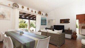 A dining area with a table and chairs, a sofa, and a television. - Venere Comfortable Holiday Residence (Maracalagonis)