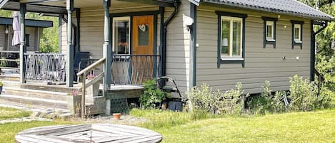 Ett hus med en veranda, en täckt uteplats och ett picknickbord i förgrunden.