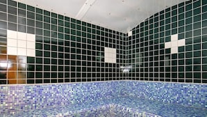 Zona de piscina con baldosas, borde de mosaico azul y techo blanco.
