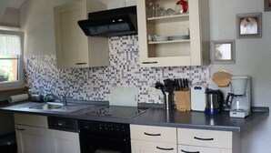 A compact kitchen with a dishwasher, oven, and a coffee maker.