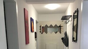 A hallway with a wooden floor, white walls, and a door at the end.