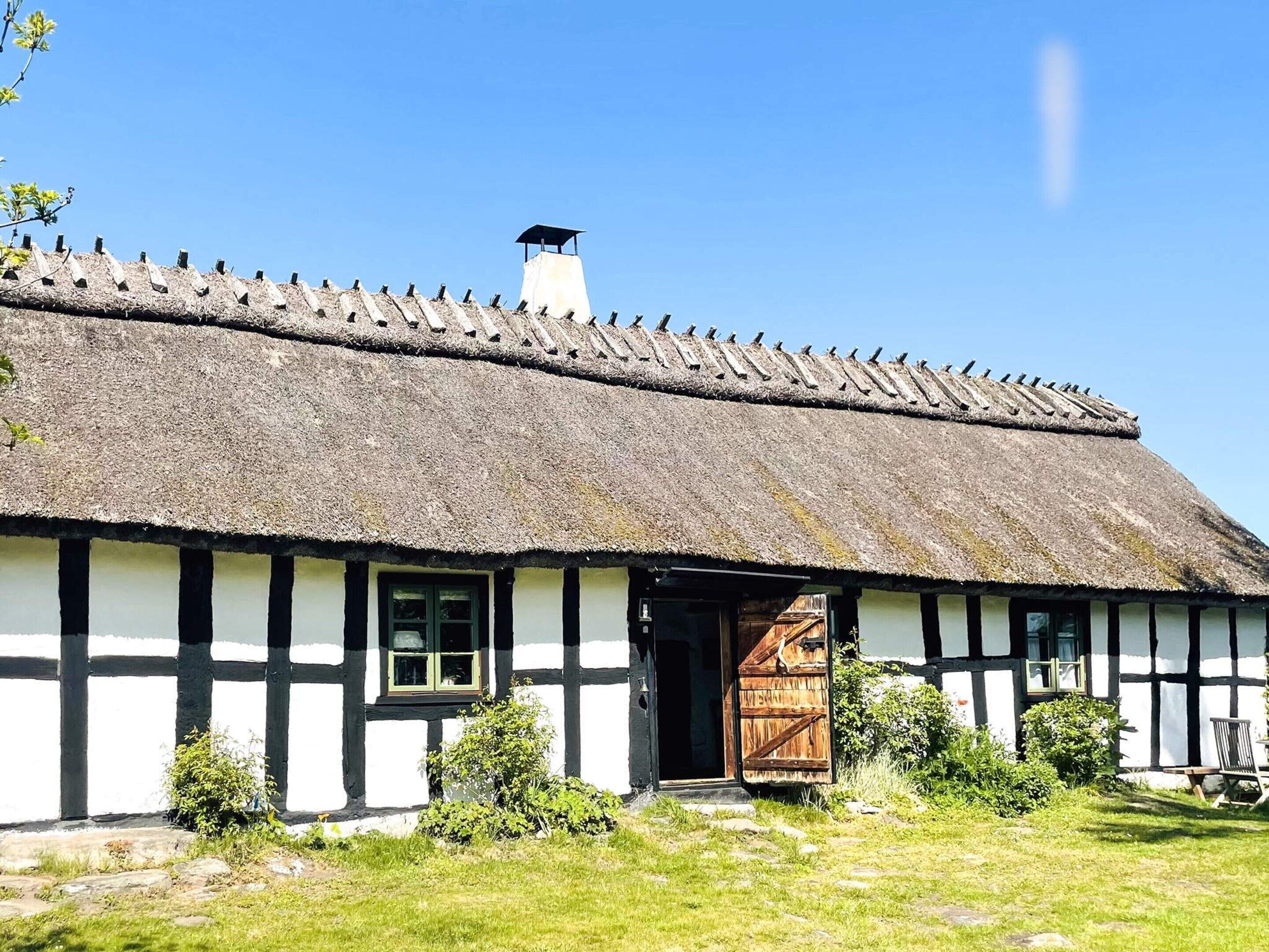 Ett traditionellt hus med halmtak, en trädörr och en skorsten.