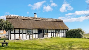 A traditional half-timbered house with a thatched roof, a small garden, and a bench. - 6 Person Holiday Home in Degeberga (Degeberga)