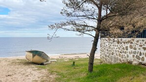 A beach with a boat, a stone wall, and a tree. - 6 Person Holiday Home in Degeberga (Degeberga)