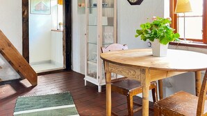 A dining area with a wooden table, chairs, a cabinet with glass doors, a clock, and a window with a lamp. - 6 Person Holiday Home in Degeberga (Degeberga)