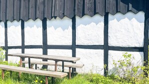A traditional building with a black and white exterior, a window with green trim, and a wooden bench in front. - 6 Person Holiday Home in Degeberga (Degeberga)