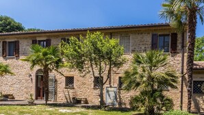 A stone building with a tiled roof, multiple windows with shutters, and a front entrance. - Belvilla by OYO Villa Dipinti (Serra San Quirico)